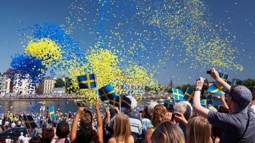 Menschen schwenken Schweden-Flaggen und blaue und gelbe Luftballons steigen in den Himmel © Ola Ericson_imagebank.sweden.se Foto: Ola Ericson